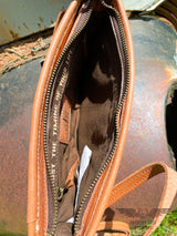 Image of interior of the Yipee Kiyay Claire crossbody purse. Brown cloth interior with zipper pocket, leather STS branded patch, and inspirational quote "Trust the timing of your life". Zipper closure.